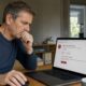 Person blickt besorgt auf eine verdächtige E-Mail am Laptop – Symbolbild Phishing