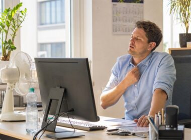 Bueroangestellter schwitzt am Schreibtisch im heissen Buero