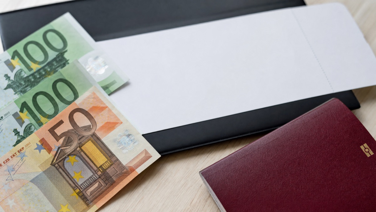 Euro-Geldscheine neben Bordkarte und Reisepass
